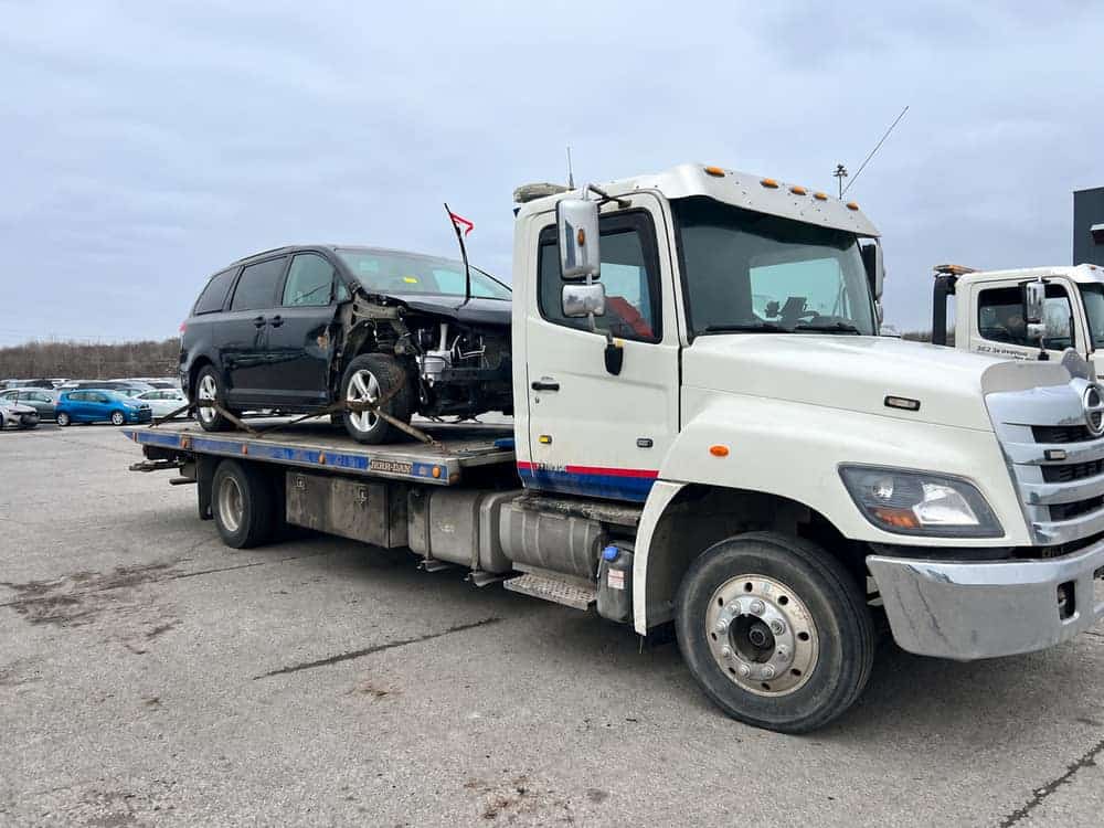 Fourgonnette accidentée sanglée sur le plateau d'une remorqueuse de Recyclage Autos B2